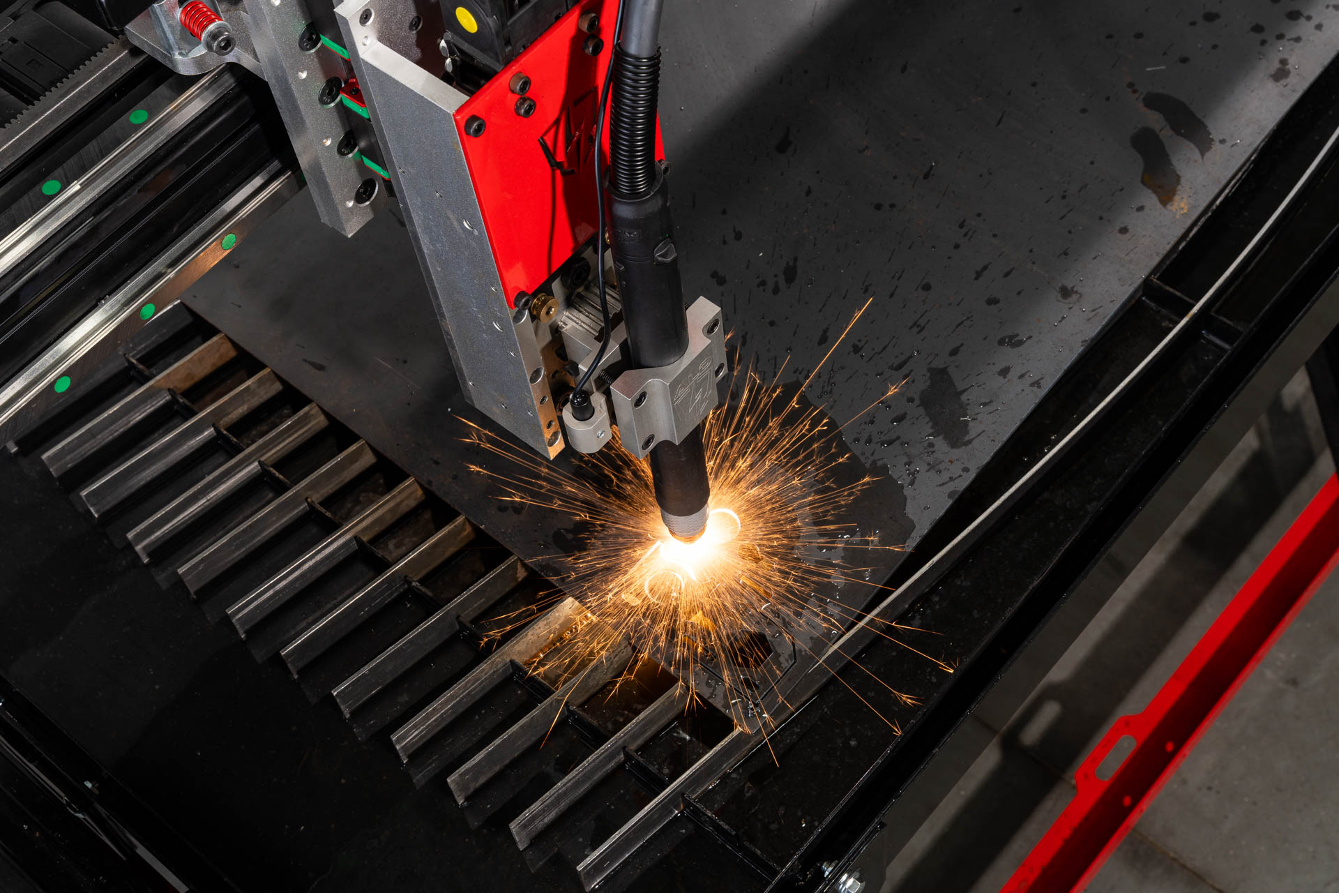 Arclight Dynamics CNC plasma table mid-cut — sparks erupting from the cut point on a steel plate.