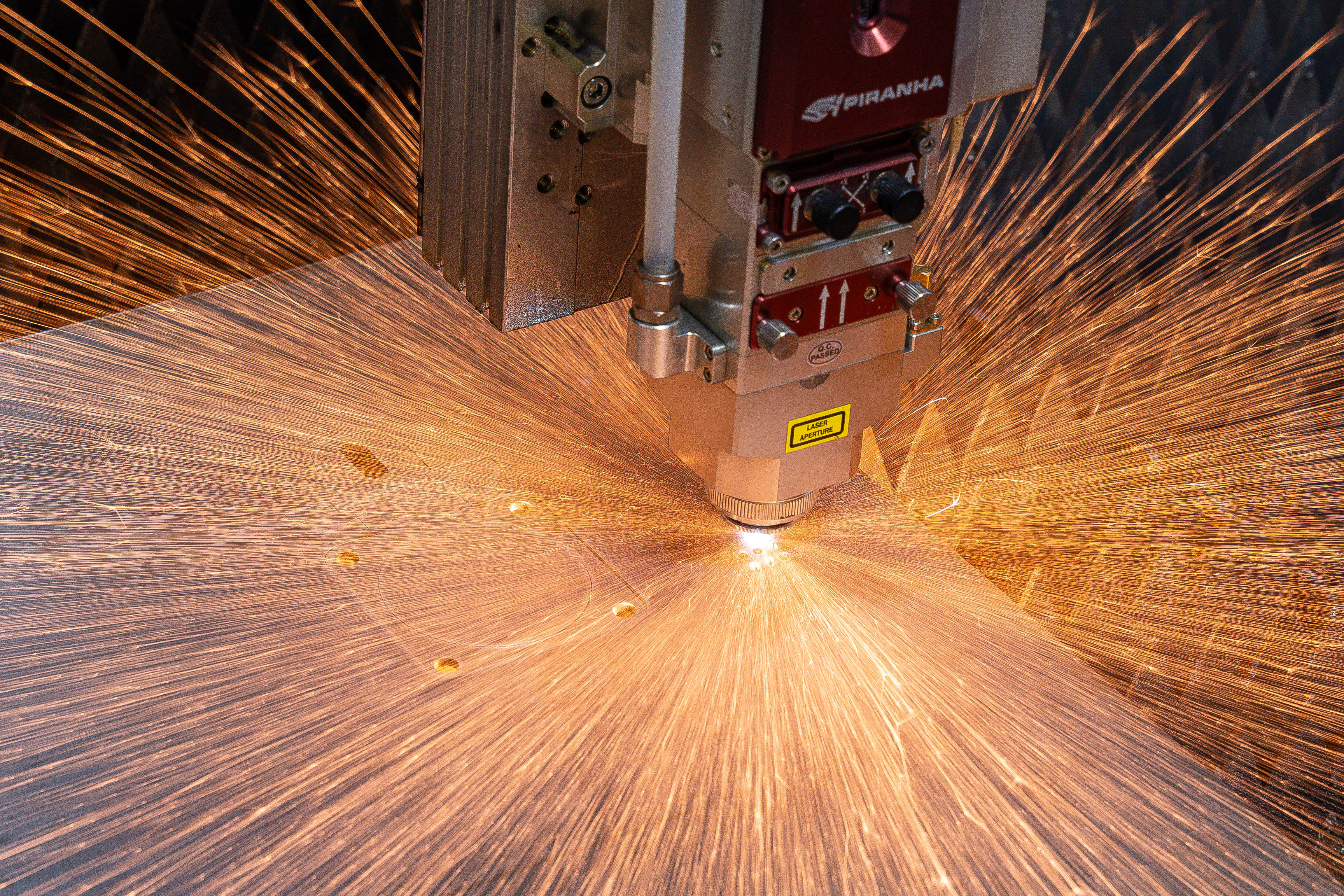 Piranha Flex 510 fiber laser mid-cut — sparks erupting in 360 degrees from cut point.